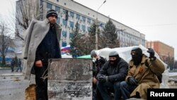 Para pengunjuk rasa pro-Rusia menghangatkan diri mereka di depan kantor pemerintah di Luhansk, Ukraina Timur (11/4).