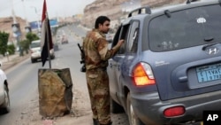 一位也门士兵在一处通往美国驻也门萨那领事馆的检查站正检查一辆汽车。