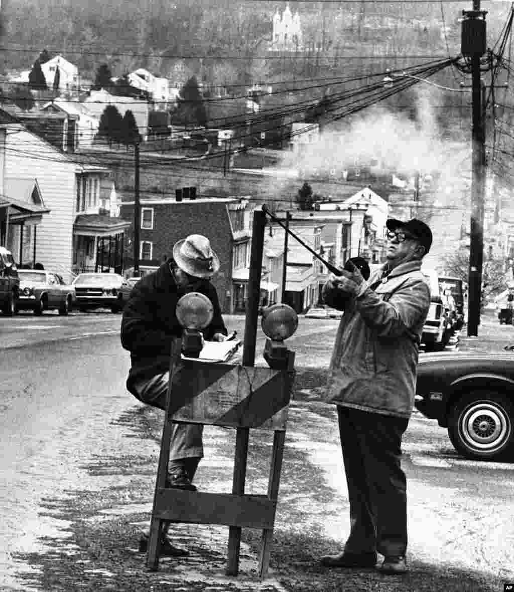 Dalam foto bertanggal April 1981 ini, Pegawai Biro Pertambangan AS memasukkan termometer ke dalam lubang di jalan utama di Centralia, Pennsylvania untuk mengukur panas dari sebuah tambang yang terbakar di kota itu sejak 1962. (AP)