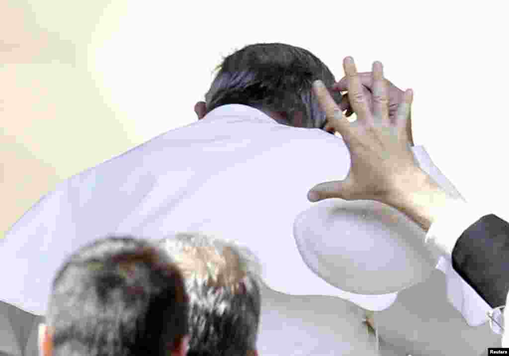Seorang anggota keamanan mencoba menangkap &#39;kopiah&#39; Paus Fransiskus yang tertiup angin pada akhir khutbah mingguan di Lapangan Santo Petrus, Vatikan.