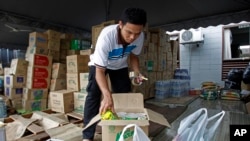 Seorang sukarelawan dari Muslim Care Malaysia Society mengepak mie instan di sebuah kotak untuk dikirimkan ke daerah yang dilanda banjir di wilayah timur, di Shah Alam, di luar Kuala Lumpur, Malaysia, Sabtu, 27 Desember 2014. Perdana Menteri Malaysia Najib Razak mengatakan pada hari Jumat ia mempersingkat liburannya di AS untuk memimpin upaya penanggulangan banjir terburuk di negara tersebut yang telah menewaskan lima orang dan menyebabkan lebih dari 100.000 orang mengungsi. (AP Photo/Lai Seng Sin)