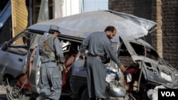 Polisi Afghanistan menginspeksi bangkai bus mini yang dihancurkan bom di Jalalabad, provinsi Nangarhar, Kamis (21/4).