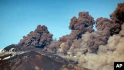 A smoke column comes out of the Etna volcano in Catania, Italy, Monday, Dec. 24, 2018. The Mount Etna observatory says lava and ash are spewing from a new fracture on the active Sicilian volcano amid an unusually high level of seismic activity. 
