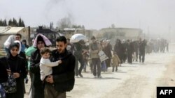 Des civils fuient la région de Hammouriyé dans l'enclave rebelle de la Ghouta orientale, après environ un mois de bombardements du régime syrien, le 15 mars 2018 