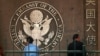 FILE - People waiting to apply for visas sit outside the U.S. Embassy in Beijing.