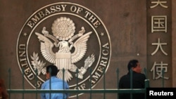 FILE - People waiting to apply for visas sit outside the U.S. Embassy in Beijing.