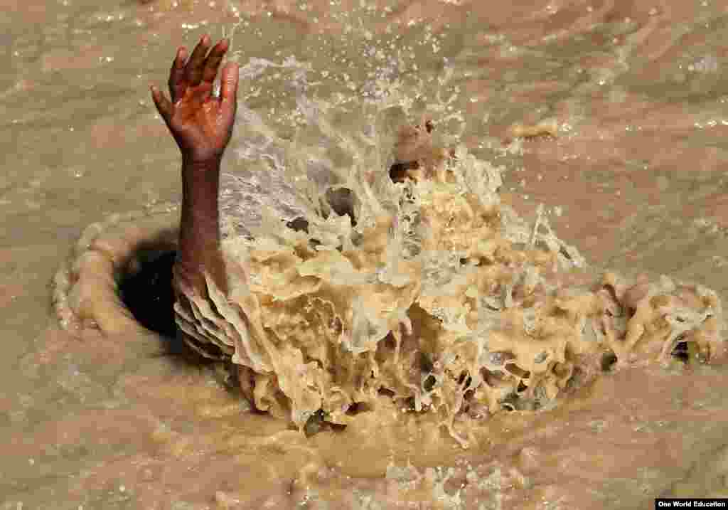 Seorang anak laki-laki berenang di air yang bercampur lumpur di Kabul, Afghanistan. 