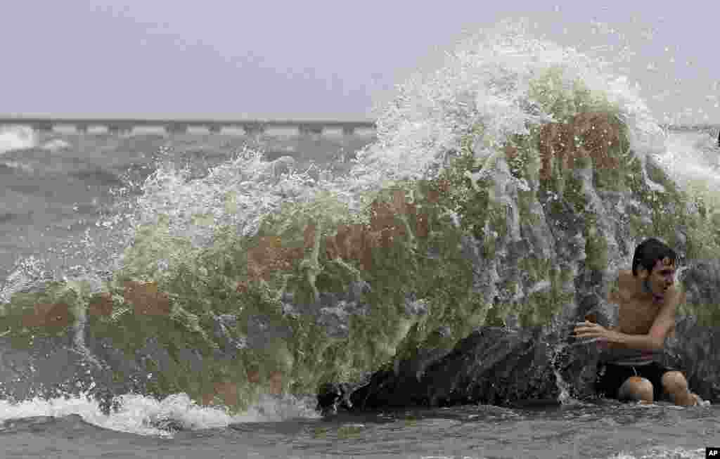 Brady Dayries is hit by a wave as winds from Tropical Storm Barry push water from Lake Pontchartrain over the seawall in Mandeville, Louisiana, July 13, 2019.