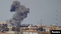 FILE - A plume of smoke rises above a building after an airstrike by the U.S.-led coalition battling the Islamic State group, in Tikrit, Iraq, March 27, 2015. 