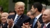 FILE - President Donald Trump, surrounded by Republican congressmen, acknowledges House Speaker Paul Ryan in the Rose Garden of the White House in Washington, May 4, 2017, after the House pushed through a health care bill. With midterm elections looming in 2018, Republican members of the House are pondering how far to distance themselves from Trump.