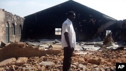 FILE - A picture taken on Jan. 24, 2010, shows a Christian resident of the Nigerian city of Jos standing near a church burnt in ongoing sectarian violence.