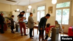 People cast their ballots during a vote on whether to give every adult citizen a basic guaranteed monthly income of 2,500 Swiss francs ($2,560), in a school in Bern, Switzerland, June 5, 2016.