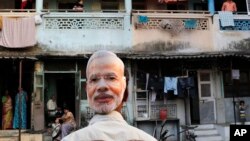 FILE - A supporter of India's main opposition Bharatiya Janata Party (BJP) wears a mask depicting the face of Prime Minister candidate Narendra Modi, during an election rally in Mumbai, India, Wednesday, April 9, 2014.