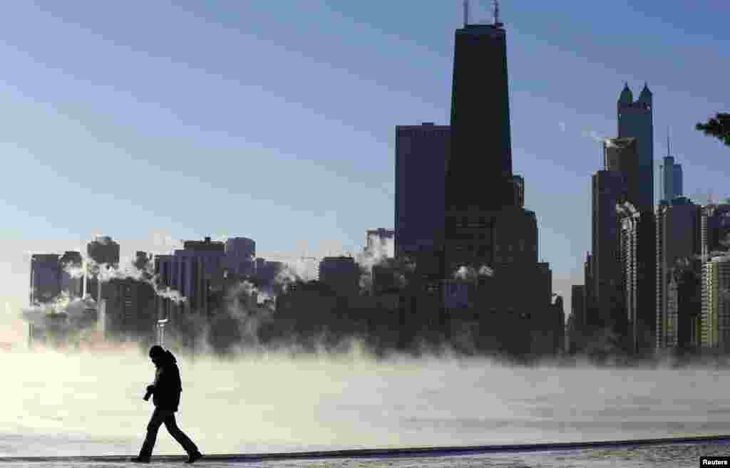 Seorang pria berjalan di tengah kota Chicago, Illinois, dengan latar belakang kabut udara dingin dari Danau Michigan, 6 Januari 2014.