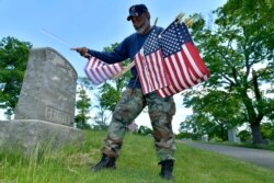 Bob Workman of Boston, a retired Marine Gunnery Sgt., and past commander of the Boston Police VFW, replaces flags at veteran's graves ahead of Memorial Day on May 27, 2021, in the Fairview Cemetery in Boston.