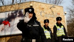 在加拿大驻北京大使馆外的一名中国警察向摄影记者打出禁止的手势。（2018年12月20日）