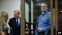 Paul Whelan, a former U.S. Marine, who was arrested in Moscow at the end of last year, right, looks through a cage's glass as his lawyers talk to each other in a court room in Moscow, Russia, Jan. 22, 2019.