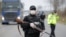 FILE - Police officers check motorists on a road access point to Tandarei, eastern Romania, April 4, 2020, after authorities imposed a severe quarantine status on the city.