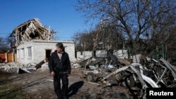 Seorang laki-laki berdiri di depan puing-puing sebuah rumah yang rusak akibat serangan senjata berat di Donetsk, Ukraina timur (6/11/2014).