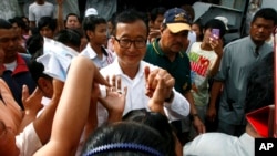 Pemimpin partai Penyelamatan Nasional Kamboja (CNRP), Sam Rainsy, menyambut warga desa saat melakukan peninjauan di salah satu TPS di pagoda Chak Angre Leu, Phnom Penh, Kamboja (28/7).