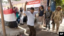 Un homme esquisse des pas de danse alors que des femmes entonnent des chants patriotiques devant un bureau de vote lors du deuxième jour de la présidentielle au Caire, en Egypte, le 27 mars 2018. 