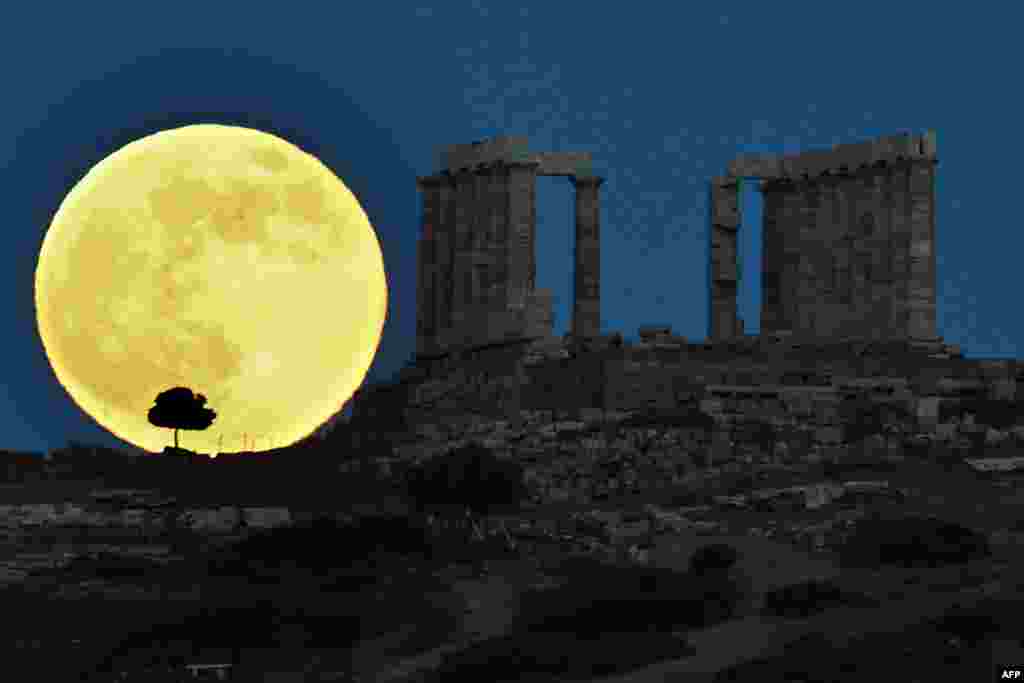 Supermoon terbit di sebelah kuil Poseidon kuno Yunani di Cape Sounion, sekitar 65 km Athena selatan, 23 Juni 2013. 