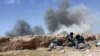 FILE - In this picture released May 20, 2015, by the website of Islamic State (IS) militants, IS fighters take cover during a battle against Syrian government forces on a road between Homs and Palmyra, Syria.