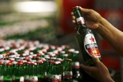 Seorang pekerja PT Multi Bintang Indonesia Tbk. memegang sebotol bir Bintang untuk pengecekan kualitas di sebuah pabrik bir di Jakarta 17 April 2015. (Foto: REUTERS/Beawiharta)