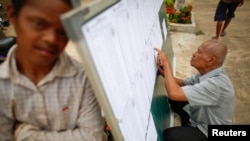 Seorang pria memeriksa daftar pemberi suara di TPS wilayah Phnom Penh(27/7).
