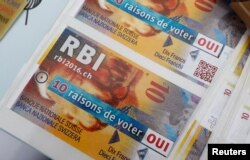 FILE - Promotional leaflets for the "Unconditional Basic Income" are pictured on the Plainpalais square in Geneva, Switzerland, May 14, 2016. Swiss voters determine the referendum's outcome Sunday.
