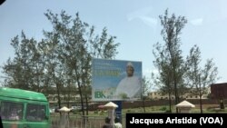 Une dame transportée sur un taxi-moto passe devant un panneau d’affichage de campagne du président sortant Ibrahim Boubacar Keita à Bamako, Mali, 27 juillet 2018. (VOA Afrique/Jacques Aristide)