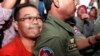 Hong Sok Hour, left, a senator from the opposition Cambodia National Rescue Party, is escorted by riot police officers, center, at Phnom Penh Municipal Court in Phnom Penh, Cambodia, Oct. 2, 2015. 