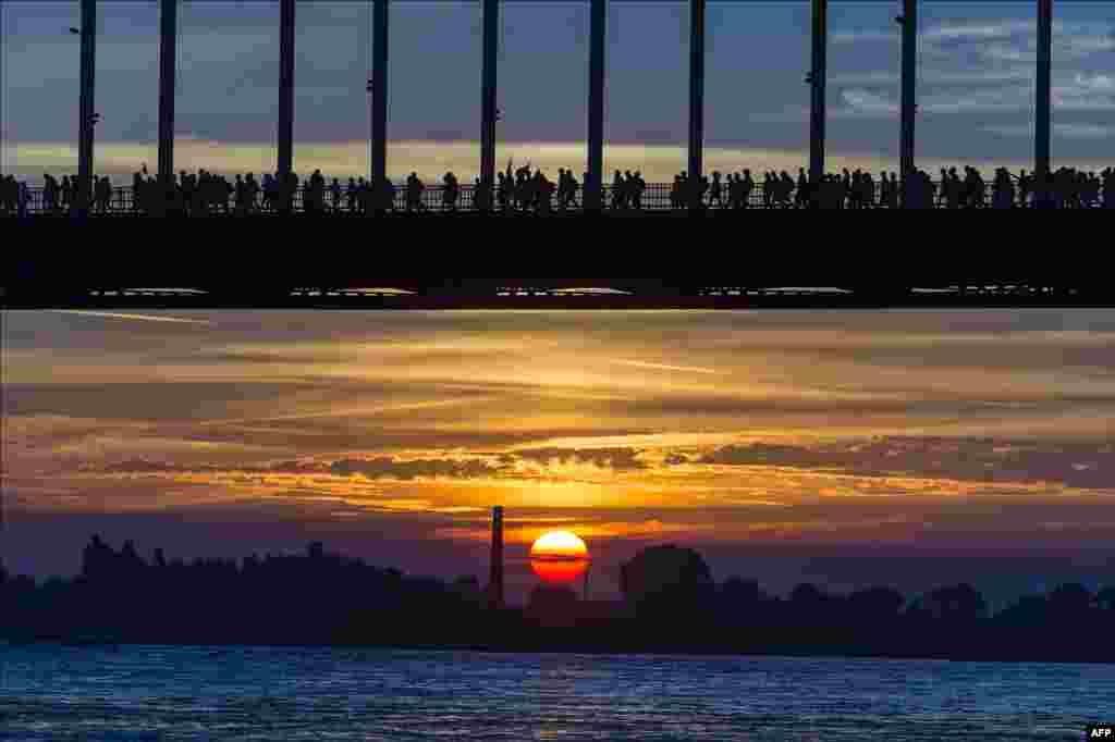 Warga menyeberangi Sungai Waalbrug saat matahari terbenam dalam acara tahunan &quot;Vierdaagse&quot; di kota Nijmegen, Belanda.