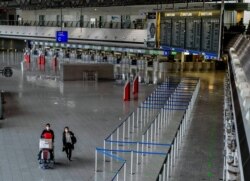 A couple with face masks walks through the empty Terminal 1 at the airport in Frankfurt, Germany, May 9, 2020.