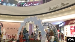 ប្រជាជន​កម្ពុជា​ថតរូប​ជាមួយ​នឹង​ការតុបតែង​សម្រាប់​ពិធីបុណ្យ​គ្រឹស្តម៉ាស​ដែល​ជាបុណ្យ​របស់​សាសនា​គ្រឹស្ត​នៅ​ក្នុងផ្សារ​ទំនើប​កាល​ពីថ្ងៃ​ទី២៤ ខែ​ធ្នូ ឆ្នាំ២០១៨ ក្នុង​រាជធានី​ភ្នំពេញ។ (ទុំ ម្លិះ/VOA)