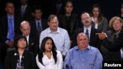 Members of the audience look on as U.S. President Barack Obama (R) speaks as he debates Republican presidential nominee Mitt Romney during the second U.S. presidential debate in Hempstead, New York October 16, 2012.
