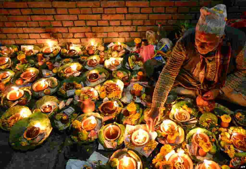 Seorang pria Hindu menyalakan lampu minyak untuk mengenang anggota keluarga yang meninggal pada festival Balachaturdashi di Candi Pashupatinath, Kathmandu, Nepal.
