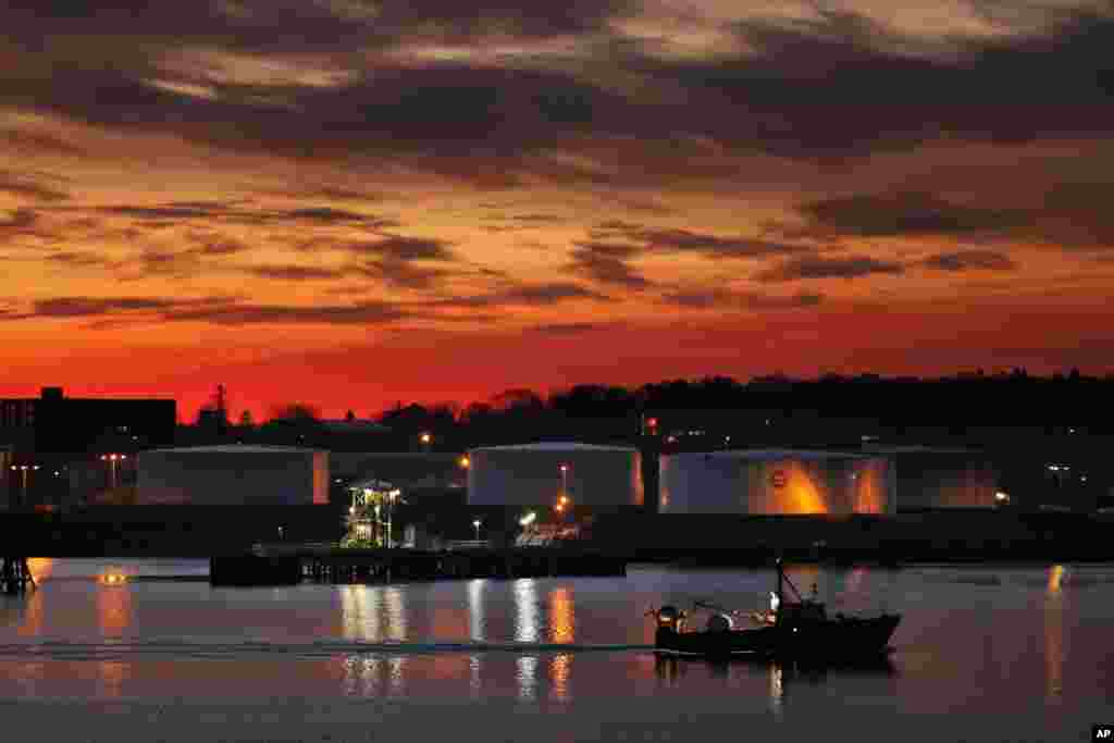 Langit berwarna merah menyala menyambut kapal pukat nelayan kembali ke pelabuhan, pada dini hari menjelang matahari terbit di kota Portland, negara bagian Maine, AS. 