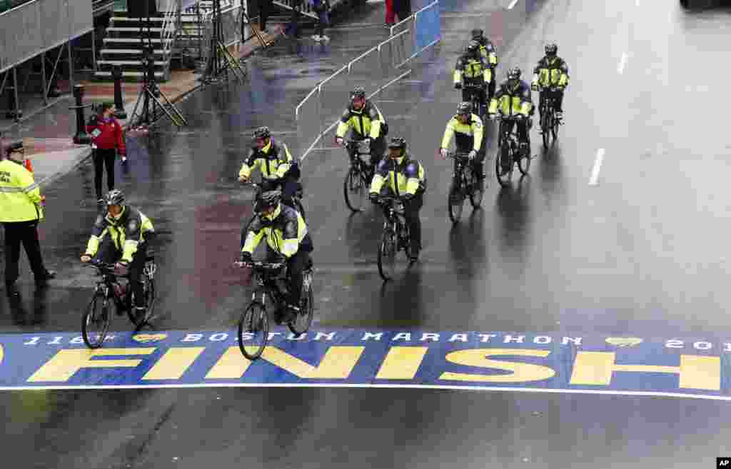 Polisi bersepeda melintasi garis finish Maraton Boston sebelum acara penghargaan bagi para anggota keluarga dan penyintas pemboman Maraton Boston di Jalan Boylston (15/4). (AP/Elise Amendola)