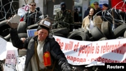 一名亲俄抗议者4月15日在乌克兰东部一座政府大楼外用石块砸墙