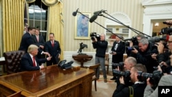 唐纳德·川普在就任总统后，在白宫的椭圆形办公室签署了他的首道行政命令，指令联邦机构放松与前任奥巴马总统全面医疗保健法有关的规定。（2017年1月20日）