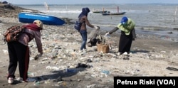 Para relawan memunguti sampah plastik yang banyak berserakan di pantai Kenjeran sisi timur Jembatan Suramadu (Foto: VOA/Petrus Riski)