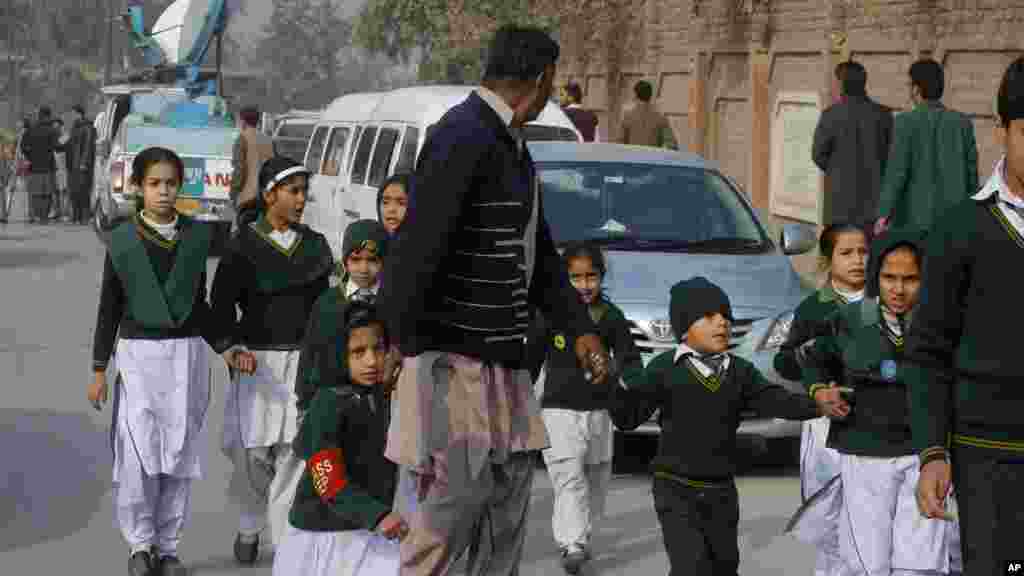Un agent de sécurité en civil escorte élèves sauvés de l&#39;école à proximité lors d&#39;une attaque des talibans à Peshawar, au Pakistan, le mardi 16 décembre 2014.