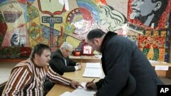 An election official assists a man with his ballot papers at a polling station in the Southern Russian city of Stavropol, March 13, 2011