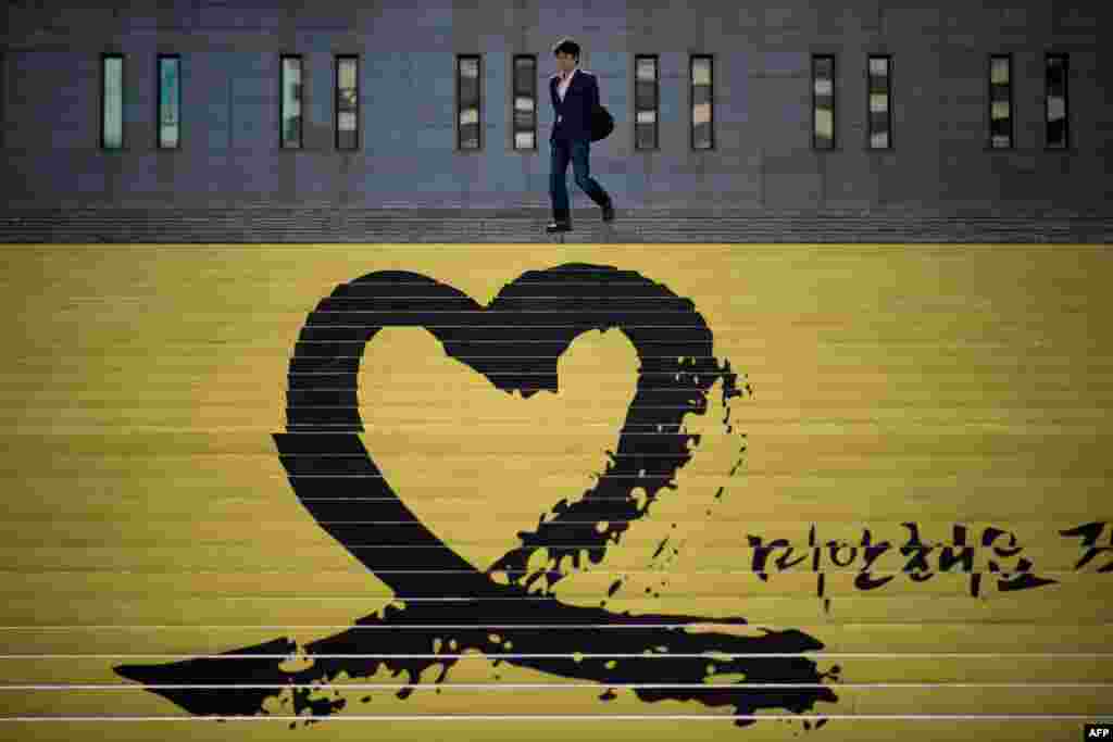 Seorang pria menuruni tangga yang dicat gambar hati untuk mengenang para korban tenggelamnya kapal feri Sewol di Seoul, Korea Selatan (9/6). (AFP/Ed Jones)