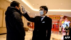 在上海的一个购物中心，一名保安在为顾客测体温。