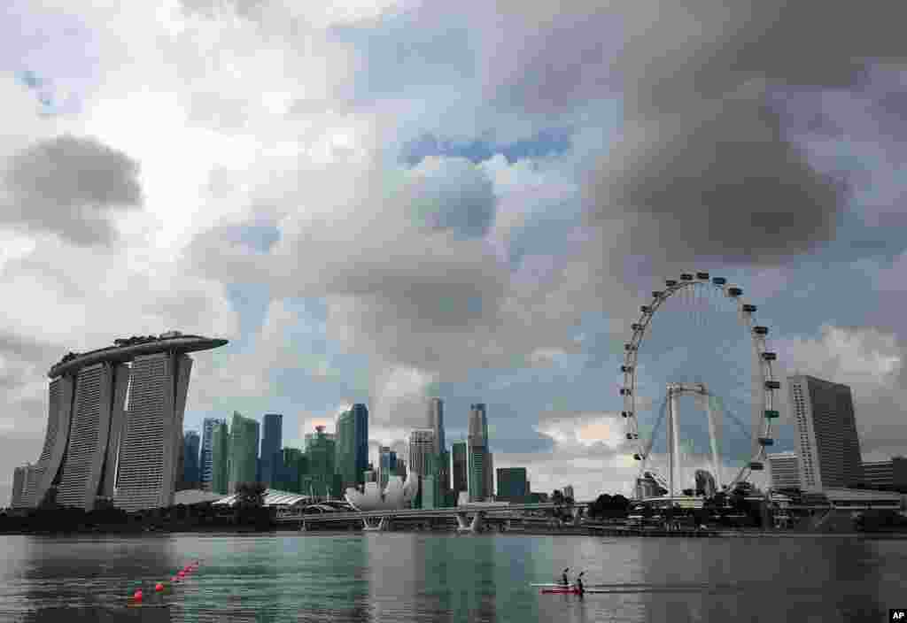 新加坡滨海湾有备受欢迎的酒店、旅游景点和摩天观景轮，水上有皮划艇（2017年3月21日）。