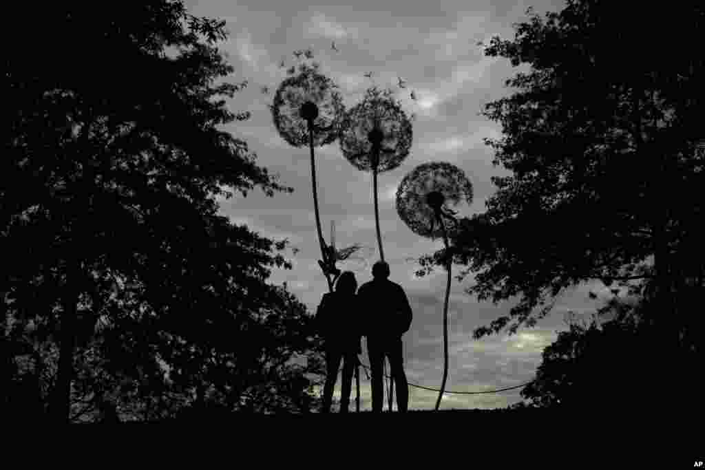 Visitors are silhouetted as they look at &quot;Dandelion Sculpture&quot; by Amy Stoneystreet and Robin Wight at the Royal Horticultural Society Garden Wisley, in the village of Wisley, near Woking, England.