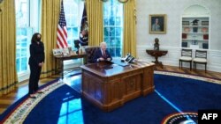 조 바이든 미국 대통령이 28일 백악관 집무실에서 카멀라 해리스 부통령이 지켜보는 가운데 저소득층 건강보험 가입 확대 행정명령에 서명하고 있다.