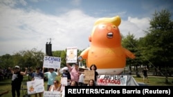 在华盛顿举行独立日庆祝活动期间，反特朗普的示威者站在“特朗普宝宝”气球前。(2019年7月4日)
